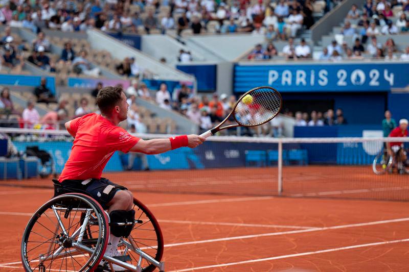 Britain's Alfie Hewett serves the ball next to his teammate Gordon Reid during the gold medal match against Japan's Takuya Miki and Tokito Oda in the Men's Doubles Wheelchair Tennis on the Court Philippe-Chatrier, at the Stade Roland-Garros, during the Paris 2024 Paralympics Games, on September 6, 2024. - AFPPIX