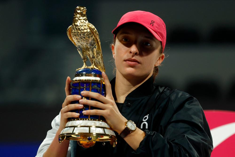 Iga Swiatek of Poland lifts the trophy during a podium ceremony after winning against Elena Rybakina of Kazakhstan (L) during their women’s singles final match at the Qatar Open tennis tournament in Doha on February 17, 2024/AFPPix