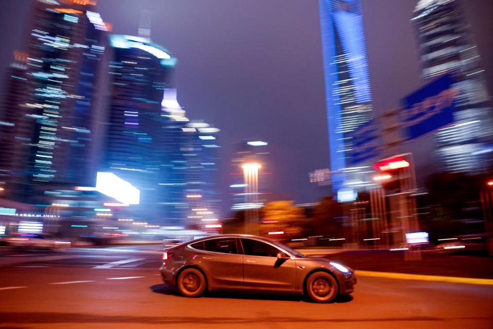 File photo: A Tesla electric vehicle (EV) drives past a crossing in Shanghai, China March 9, 2021. REUTERSpix