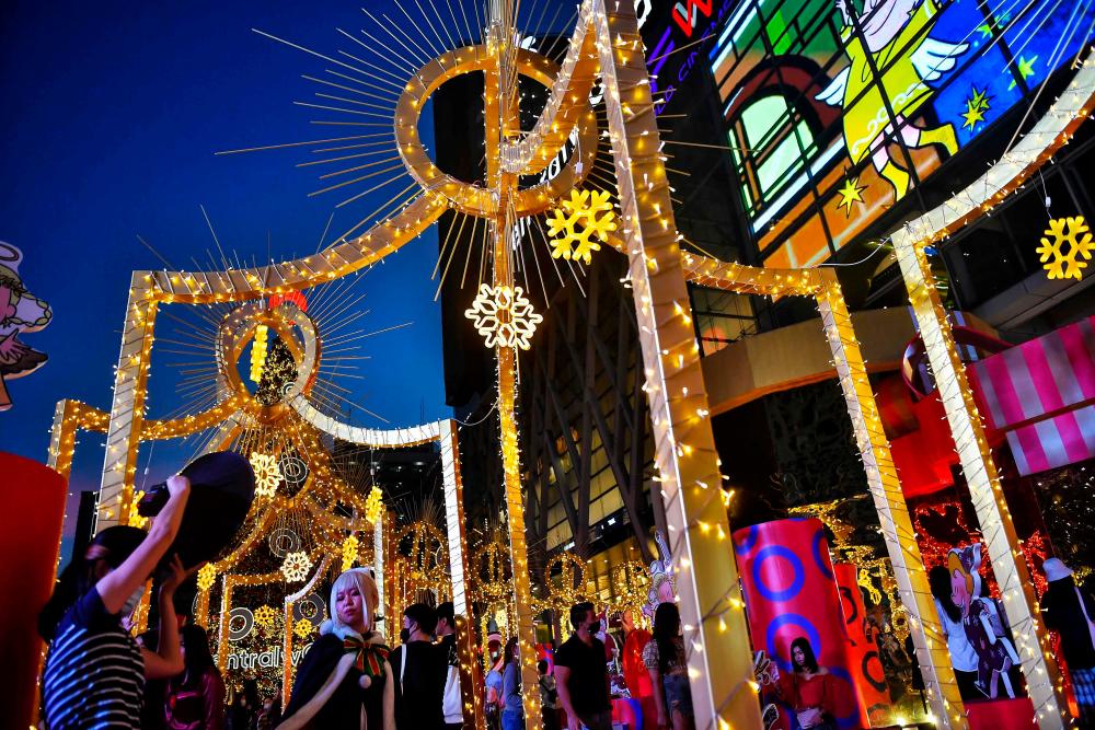 People pose for photographs amid decorations for Christmas and the New Year outside a shopping mall in Bangkok. – AFPPIX