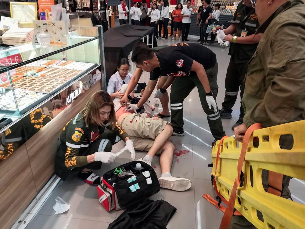 This photograph taken on Jan 9, and received from ViralPress shows paramedics helping a man wounded during a robbery at the Robinson shopping mall in the town of Lopburi, some 150km north of Bangkok. — AFP