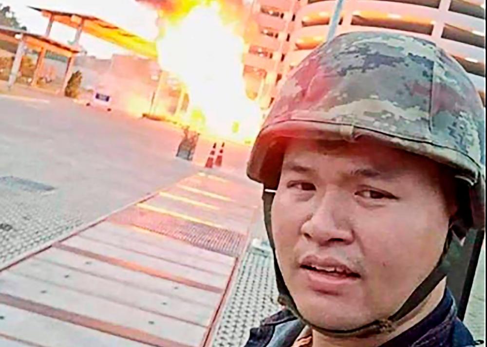 This screenshot made on Feb 8, 2020 from the Facebook livestream video of Thai soldier Jakrapanth Thomma shows him standing in front of a building on fire during an attack in the northeastern city of Nakhon Ratchasima. — AFP