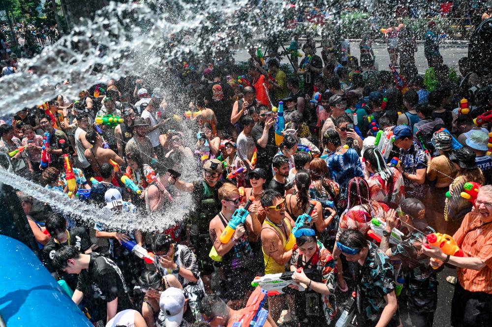 Revellers take part in mass water fights on the first day of Songkran, or Thai New Year, on Silom Road in Bangkok on April 13, 2024. - AFPPIX