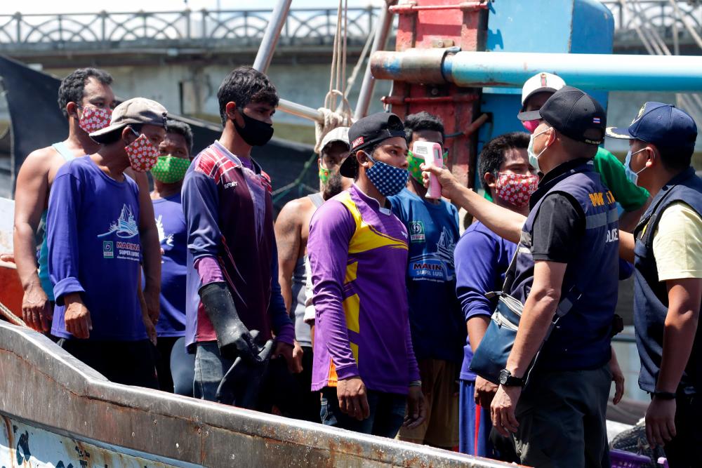 Immigration officers check the temperatures of Myanmar fisherman, as a preventive measure against the spread of the Covid-19 novel coronavirus, at the port in Pattani on April 11, 2020. - AFP