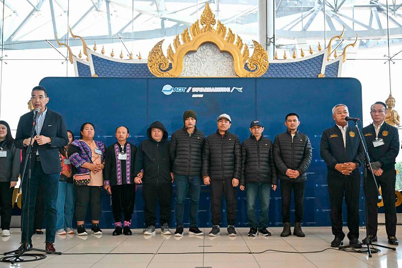 Freed Thai nationals Surasak Rumnao, Sayhian Suwannkham, Bannawat Saethao, Watchara Sriaoun and Pongsak Thaenna (collectively, in background 3rd L-R) stand with officials during a press conference after their return to Thailand at Bangkok’s Suvarnabhumi Airport on February 9, 2025, following their release in a hostage-prisoner exchange between Israel and Hamas as part of a ceasefire deal. - Manan VATSYAYANA / AFP