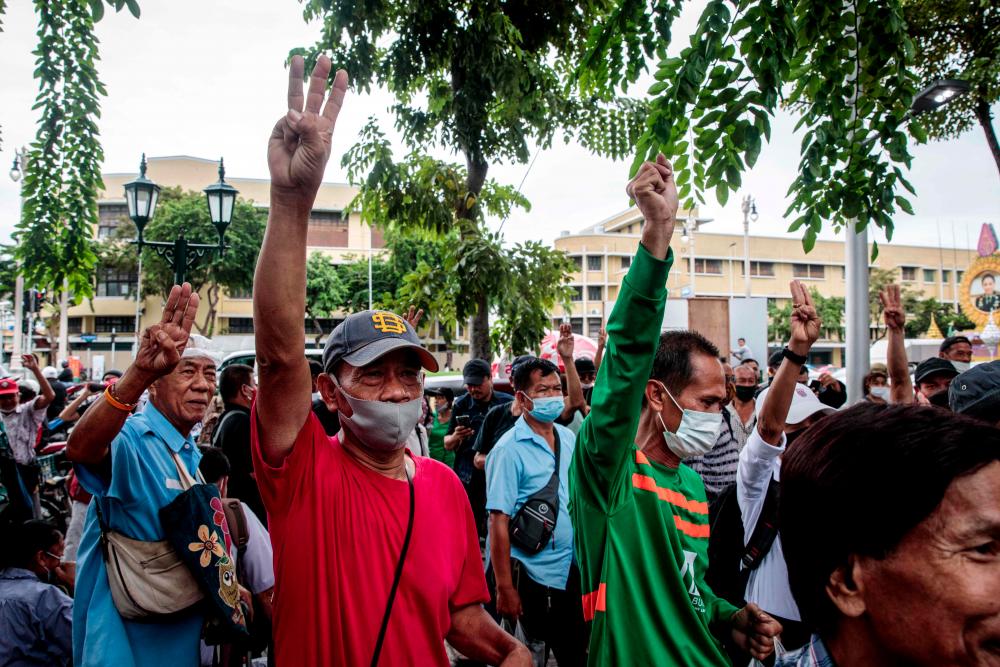 Anti-government protesters make the three-fingered Hunger Games salute at a pro-democracy rally at the 14 October 1973 Memorial in Bangkok on Sept 20, 2020. — AFP