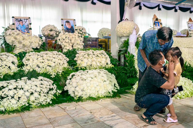 Relatives mourn in front of portraits and coffins of the victims of a school bus fire at Wat Khao Phraya Sangkharam School in Uthai Thani, on October 3, 2024. Grieving families wept as they offered prayers for 23 children and their teachers killed in a horrifying Thai school bus fire, as the government vowed a crackdown on unsafe vehicles. - AFPpix