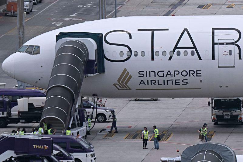 Officials gather around the Singapore Airlines Boeing 777-300ER airplane, which was headed to Singapore from London before making an emergency landing in Bangkok due to severe turbulence, as it is parked on the tarmac at Suvarnabhumi International Airport in Bangkok on May 22, 2024. - AFPPIX