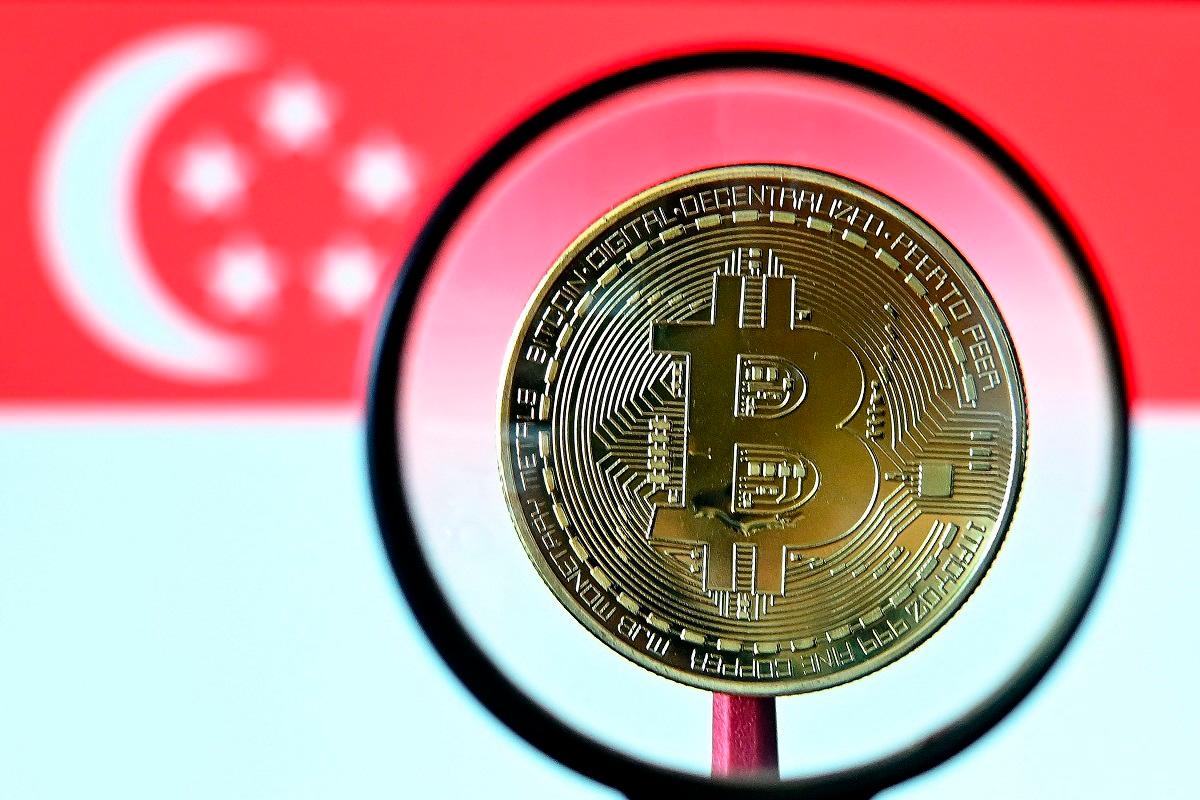 This illustration photograph taken on June 30, 2025 shows a Bitcoin cryptocurrency representation coin seen through a microscope against the backdrop of the Singapore national flag, in Bangkok. - AFPpix