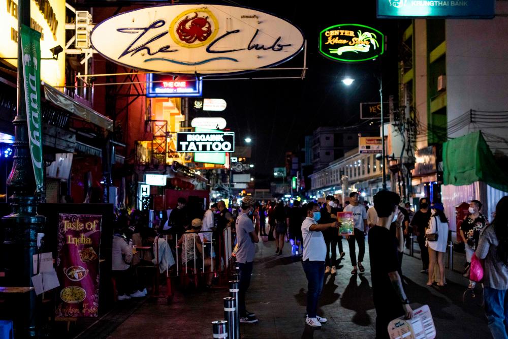 FILE: A man holds out a menu of a bar as tourists walk along the popular tourist and nightlife strip Khao San Road in Bangkok on December 10, 2021. AFPPIX
