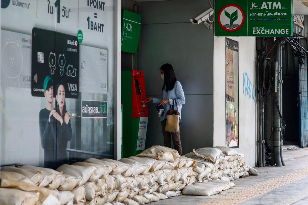 A woman uses an automated teller machine (ATM) next to sandbags, piled up outside a bank as a preventive measure amid flooding across parts of northern and central Thailand, in Bangkok on September 28, 2021. AFPpix