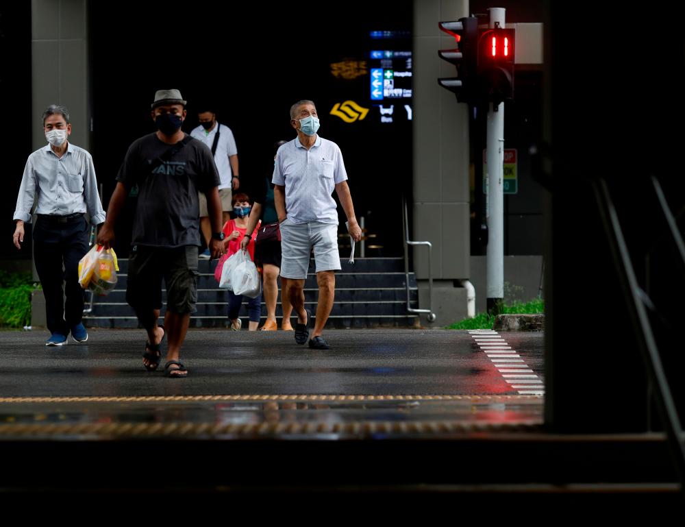 People wearing face masks cross a street amid the Covid-19 outbreak in Singapore June 1, 2020. - Reuters