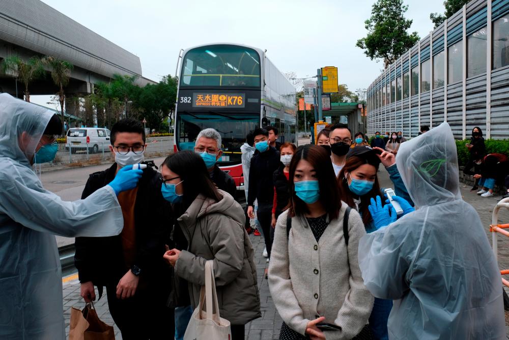 Residents wearing masks and raincoats volunteer to take temperature of passengers following the outbreak of a new coronavirus at a bus stop at Tin Shui Wai, a border town in Hong Kong, China February 4, 2020. - Reuters