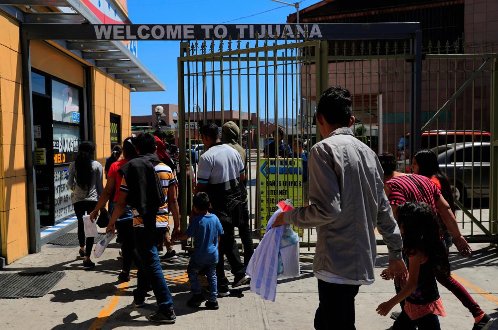Central American migrants returned from the US to Mexico under the Migrant Protection Protocols (MPP), enter a shopping mall in Tijuana, Mexico, July 18, 2019. - Reuters