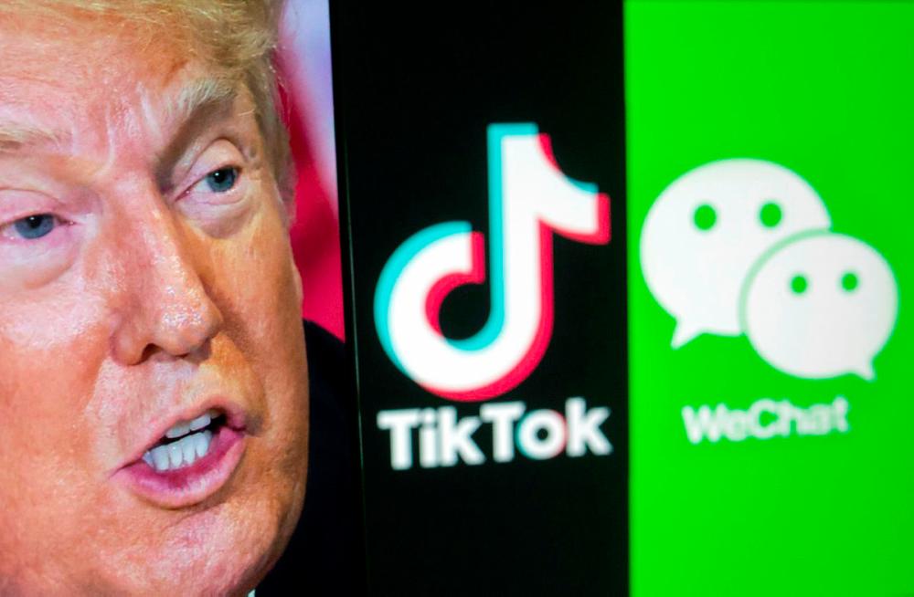 A picture of U.S. President Donald Trump is seen on a smartphone in front of displayed Tik Tok and WeChat logos.-Reuters