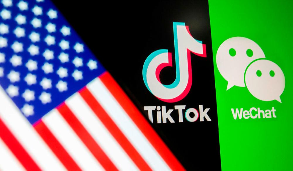 A U.S. flag is seen on a smartphone in front of displayed Tik Tok and WeChat logos. Reuters
