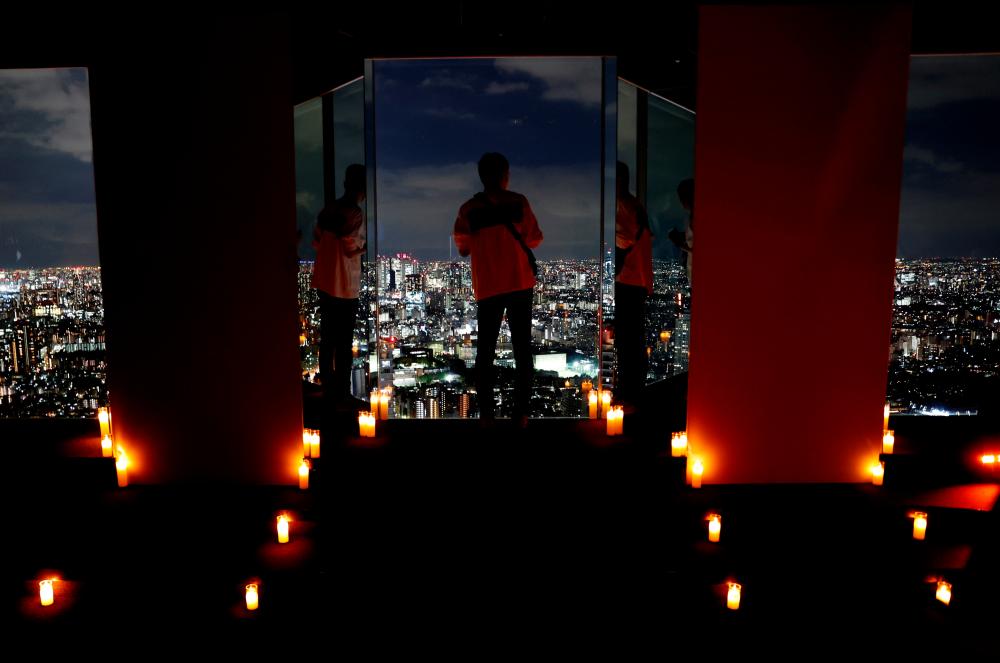 FILE PHOTO: Visitors take photos with Tokyo's night view during totally dark time event, in which all electric lights are out and candlelight is used instead, at Sunshine City's Observatory after Covid-19 controls were eased, in Tokyo, Japan, October 15, 2021. REUTERSpix
