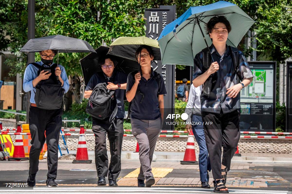 People shield themselves from the hot sun with umbrellas in Tokyo on August 27, 2025. Tokyo experienced a record 10 consecutive days of temperatures 35C or above, the weather office said on August 27. - Yuichi YAMAZAKI / AFP