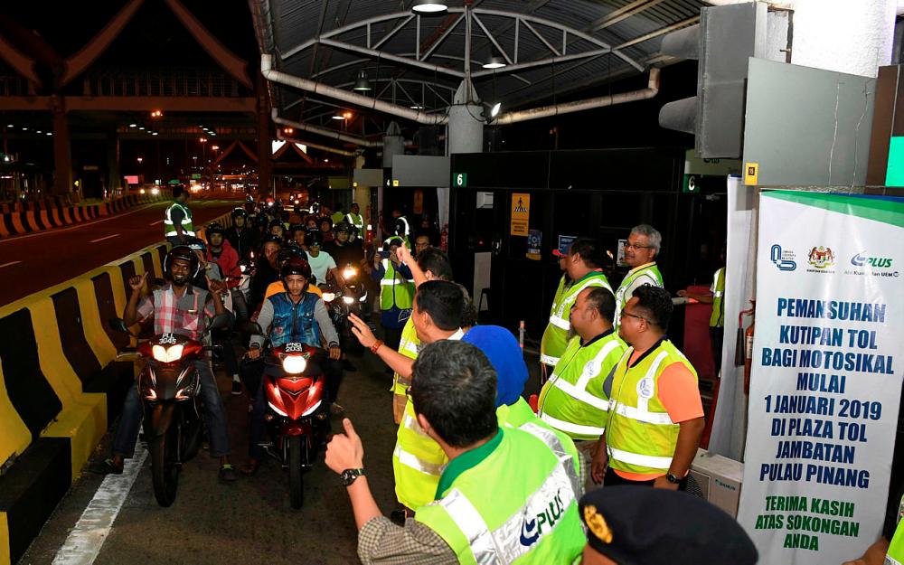 Motorcylists give the thumbs-up following the abolition of toll collection at Penang Bridge at the stroke of midnight. — Bernama