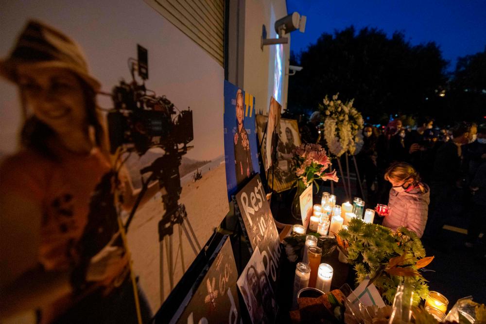 A girl pays respects near a photo of cinematographer Halyna Hutchins, who was accidentally killed by a prop gun fired by actor Alec Baldwin, at a memorial table during a candlelight vigil in her memory in Burbank, California/AFPPix