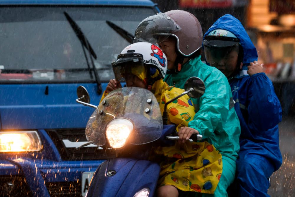 People wearing raincoats ride a motorcycle in Yilan as Typhoon Haikui makes landfall in eastern Taiwan on September 3, 2023. AFPPIX