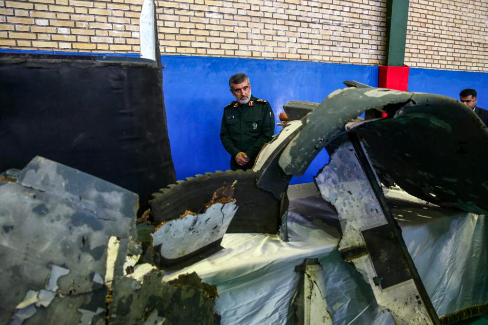 General Amir Ali Hajizadeh (C), Iran's Head of the Revolutionary Guard's aerospace division, looks at debris from a downed US drone reportedly recovered within Iran's territorial waters and put on display by the Revolutionary Guard in the capital Tehran on June 21, 2019. - AFP