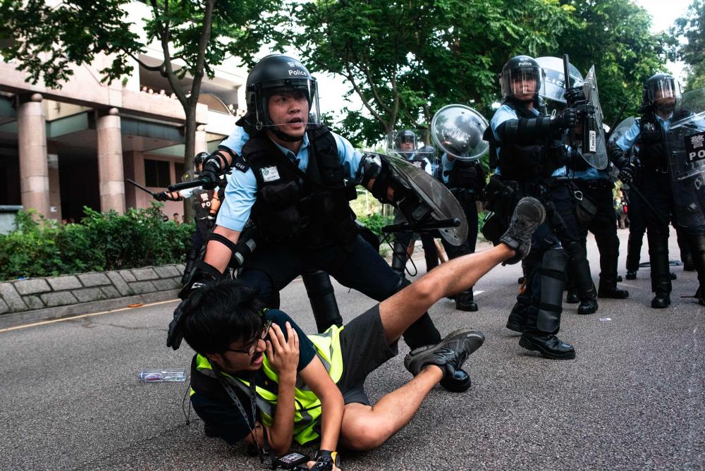 A photojournalist falls down during clashes between protesters and police at an anti parallel trading march in Sheung Shui district in Hong Kong on July 13, 2019. - AFP