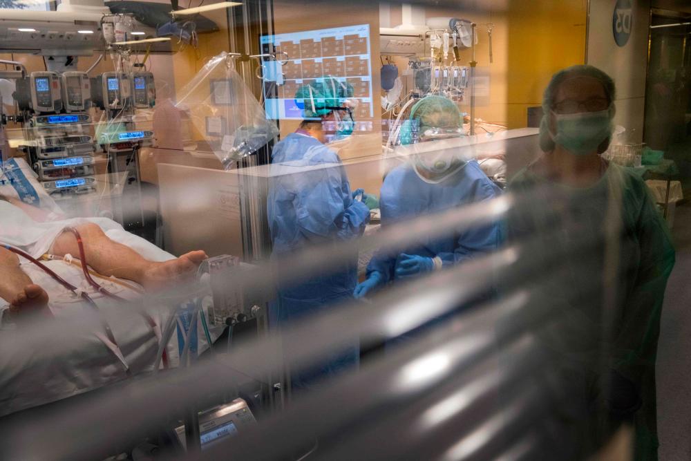Health workers attend to a Covid-19 patient at the intensive care unit of the Vall d'Hebron hospital in Barcelona on April 1, 2020. - AFP