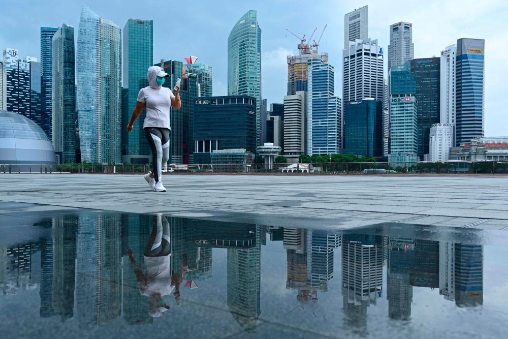 A woman, wearing a face mask as a preventive measure against the spread of the Covid-19 novel coronavirus, walks along the promenade at Marina Bay in Singapore on May 4, 2020. - AFP