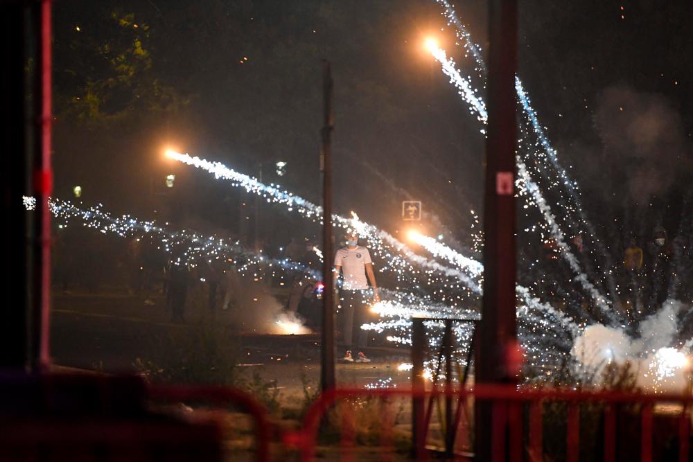 A man stands among tear gas smokes fired by French anti-riot policemen escorting Paris Saint-Germain (PSG) supporters around the Parc des Princes stadium on August 23, 2020, after the UEFA Champions League final football match between PSG and Bayern Munich played at the Luz stadium in Lisbon. - AFP