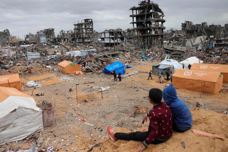 Displaced Palestinian children sit on a sand mound overlooking tents set up amid destroyed buildings in Jabalia in the northern Gaza Strip - AFPpix