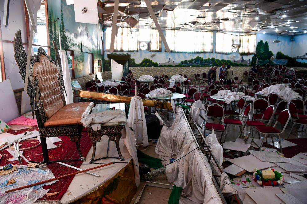 Afghan men investigate in a wedding hall after a deadly bomb blast in Kabul on August 18, 2019. — AFP