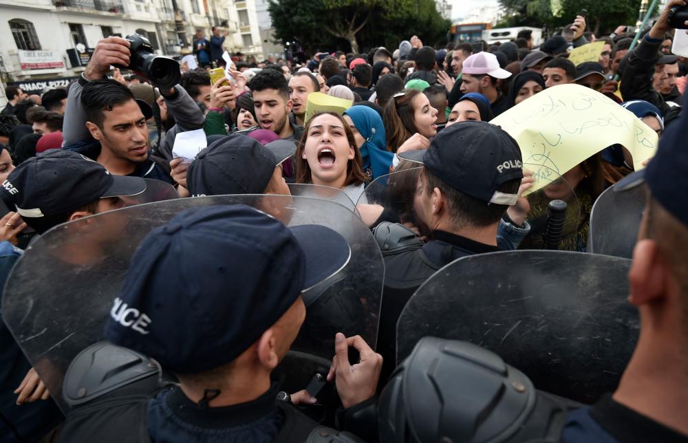 Algerian security forces contain protesters shouting slogans during an anti-government demonstration in the capital Algiers on Dec 9, ahead of the presidential vote scheduled for Dec 12. — AFP