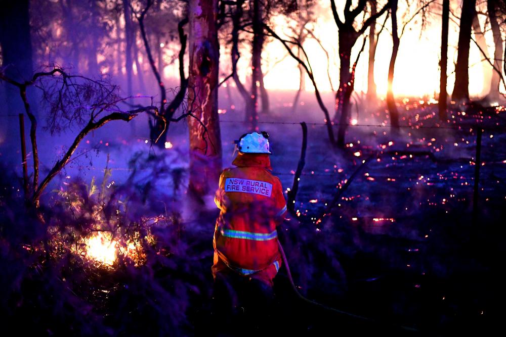 This photo taken on Dec 7, shows a firefighter conducting back burning measures to secure residential areas from encroaching bushfires at the Mangrove area, some 90-110km north of Sydney. — AFP