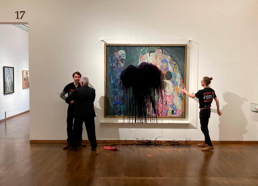 This handout picture released on November 15, 2022 by the “Last Generation” shows a climate activist of the “Last Generation” group being overpowerd whereas another one has glued himself to the painting “Death and Life” by Austrian artist Gustav Klimt after pouring black liquid over the art work at the Leopold Museum in Vienna, Austria. AFPPIX