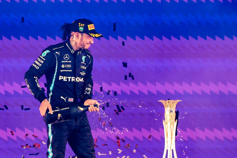 TOPSHOT - Mercedes' British driver Lewis Hamilton celebrates on the podium after winning the Formula One Saudi Arabian Grand Prix at the Jeddah Corniche Circuit in Jeddah on December 5, 2021. AFPpix