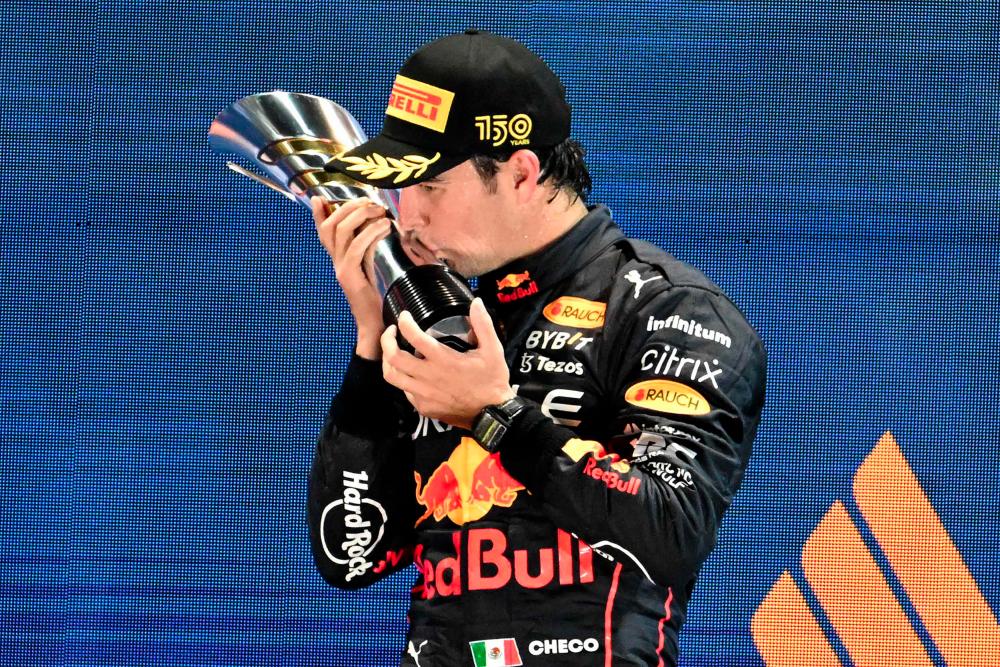 TOPSHOT - Winner Red Bull Racing's Mexican driver Sergio Perez celebrates on the podium after the Formula One Singapore Grand Prix night race at the Marina Bay Street Circuit in Singapore on October 2, 2022. - AFPPIX