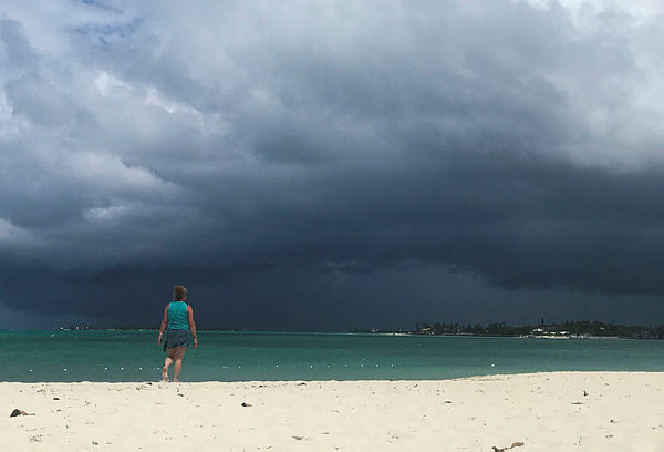 A woman walks on the beach as a storm approaches in Nassau, Bahamas, on September 12, 2019.