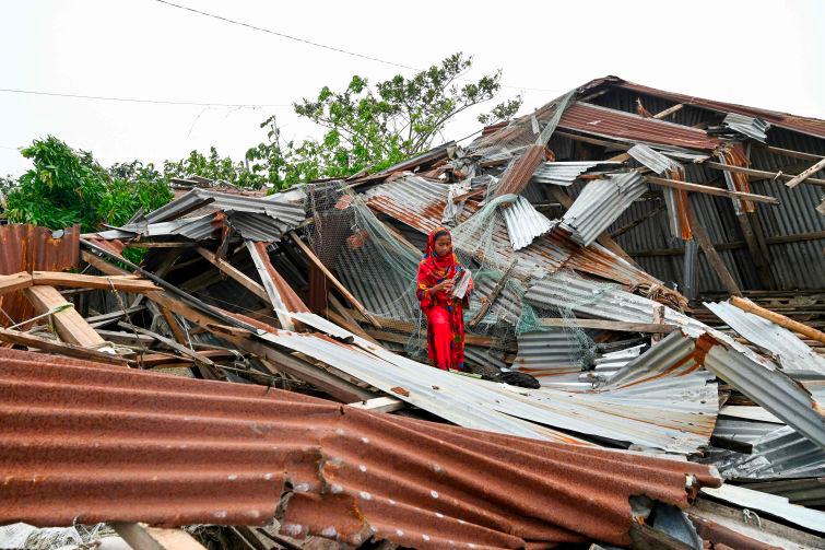 A girl walks amid her damaged house after cyclone Remal's landfall in Patuakhali on May 28, 2024. - AFPPIX