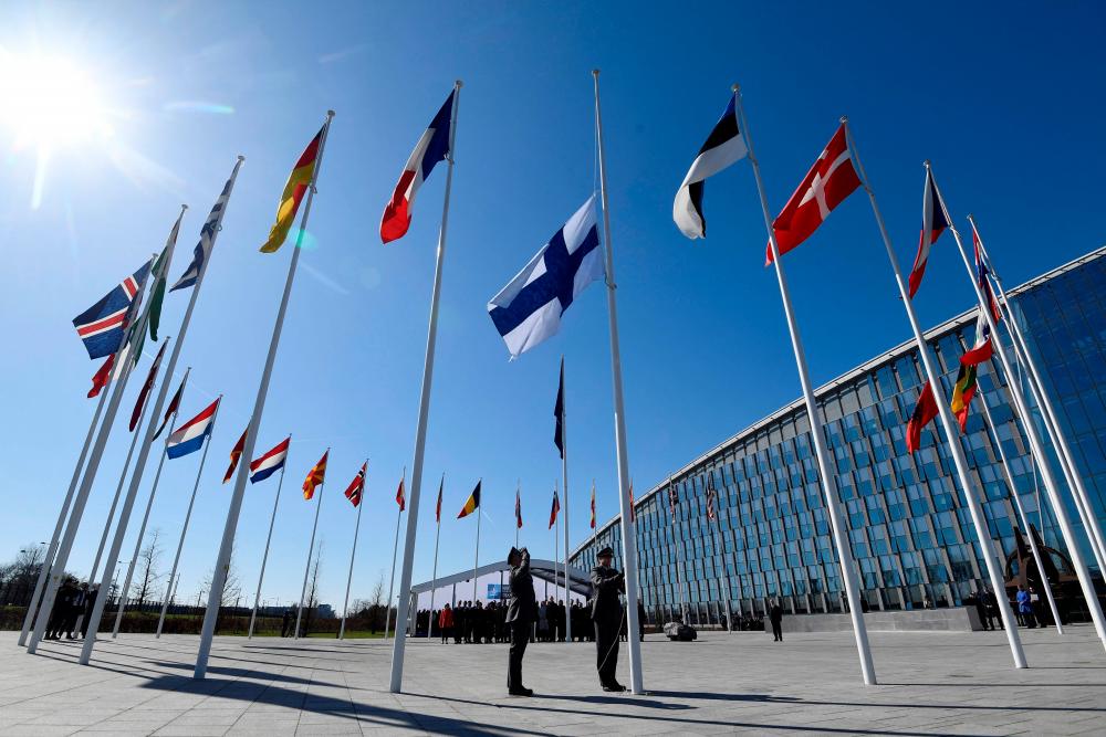 Finnish military personnel install the Finnish national flag at the NATO headquarters in Brussels, on April 4, 2023. AFPPIX