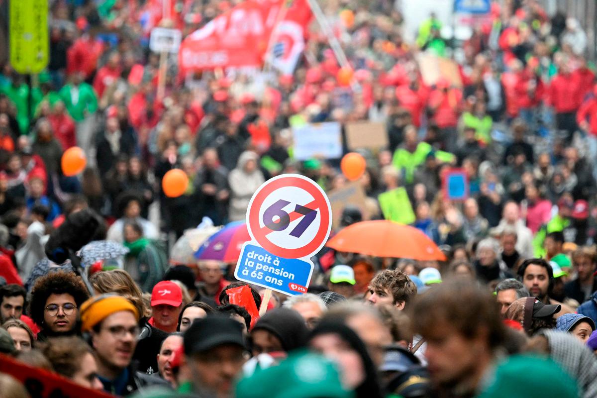 Protesters hold a slogan reading “Right to have pension at the age of 65” as they take part in a demonstration during a national day of action against the austerity of the federal Arizona government, in Brussels on October 14, 2025. - NICOLAS TUCAT / AFP