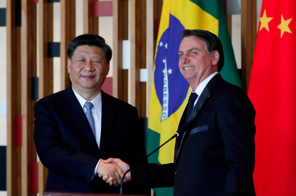 Chinese President Xi Jinping (L) and Brazilian President Jair Bolsonaro shake hands during a press statement after their bilateral meeting at Itamaraty Palace in Brasilia, Brazil, on Nov 13. — AFP