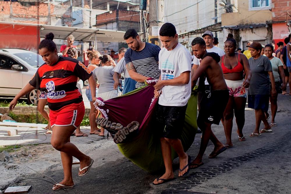 Residents of the Complexo do Alemao favela carry the corpse of a dead man during a police raid in Rio de Janeiro, Brazil/AFPPix