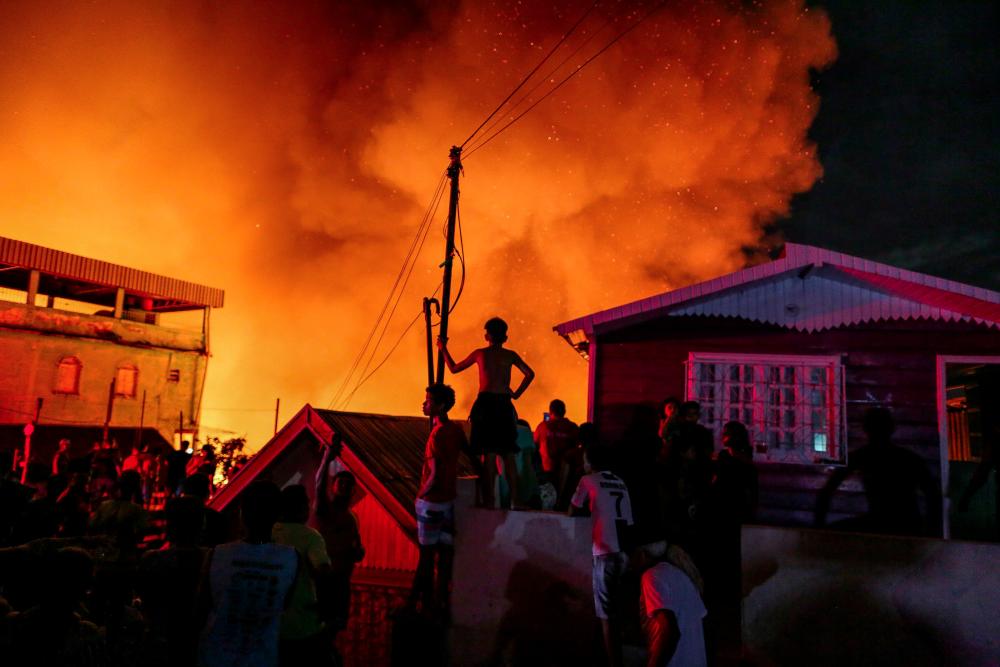 Residents of Educandos neighbourhood remain near their burning houses, as firefighters try to control a massive fire, in Manaus, Amazonas state, Brazil late Dec 17, 2018. — AFP