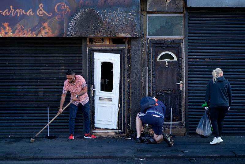 Restaurant owner Luqman Khan clears debris from the street in front of his restaurant in Middlesbrough, following rioting and looting the day before - AFPpix