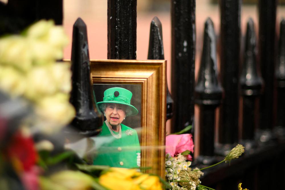 A framed photograph of Britain’s Queen Elizabeth II is seen on the railings of Buckingham Palace in central London on September 8, 2023, as well-wishers commemorate the life of Her Late Majesty Queen Elizabeth II on the first anniversary of her passing/AFPPix