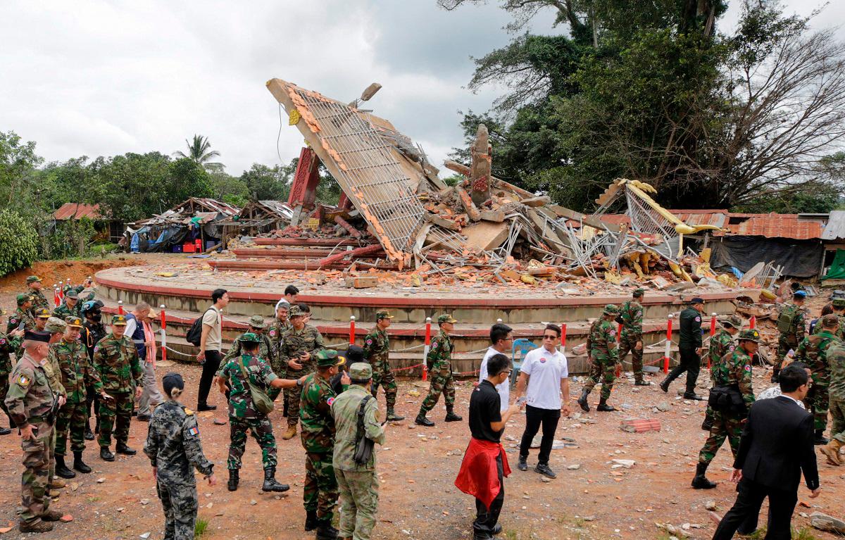 Military attaches and diplomats from 13 countries observe the implementation of the Cambodia–Thailand ceasefire agreement next to a destroyed building by the An Ses border checkpoint in Cambodia’s Preah Vihear province on July 30, 2025. - Chor Sokunthea / AFP