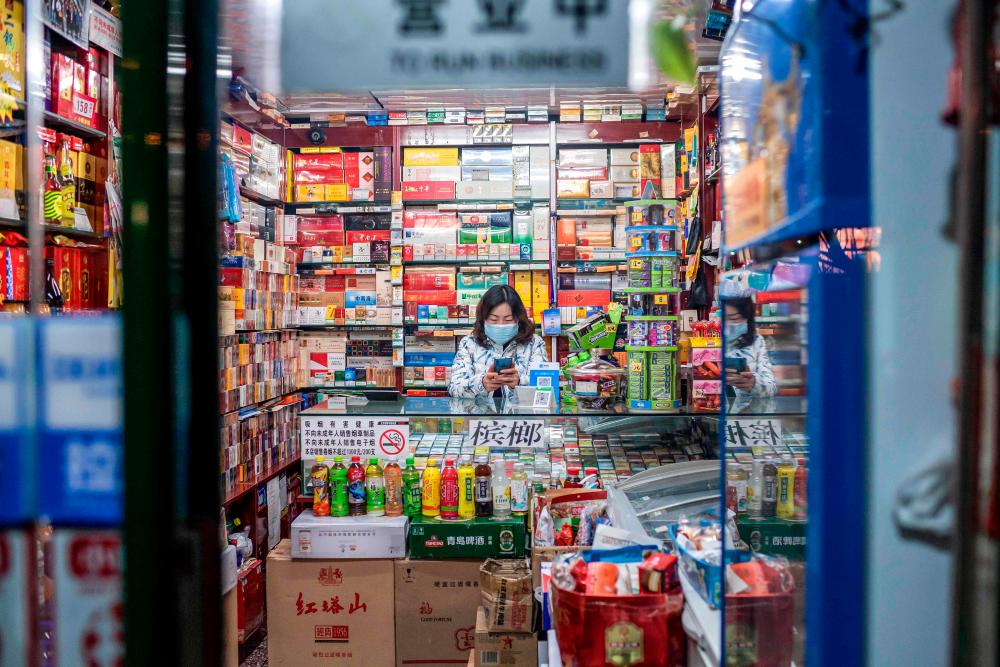 A vendor wearing a protective facemask waits for customers at a shop in Beijing on Feb 21. — AFP