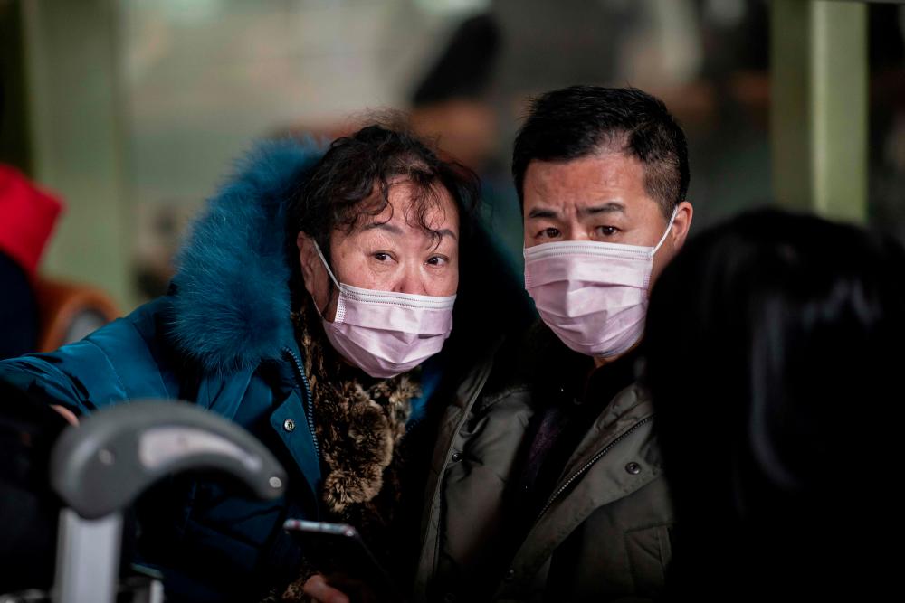 People travelling for the Lunar New Year wear protective masks as they head to the departure area at the Beijing Capital International Airport in Beijing on Jan 22. — AFP