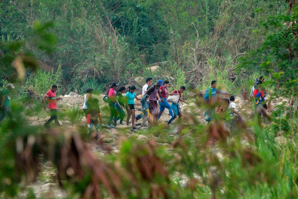 People cross through Trochas — illegal trails — across the Tachira river from San Antonio in Venezuela to Cucuta in Colombia on Feb 27, 2019. — AFP